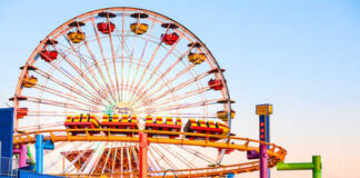 Colorful amusement park scene featuring a ferris wheel and roller coaster at sunset