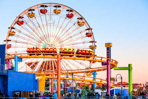 Colorful amusement park scene featuring a ferris wheel and roller coaster at sunset