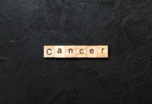 Wooden letters spelling the word 'Cancer' on a black textured background