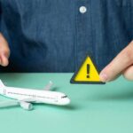 A person holding a warning sign next to a model airplane