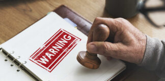 A hand applying a warning stamp on a document