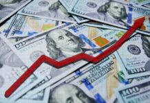 A pile of hundred dollar bills with a red upward trend line overlay