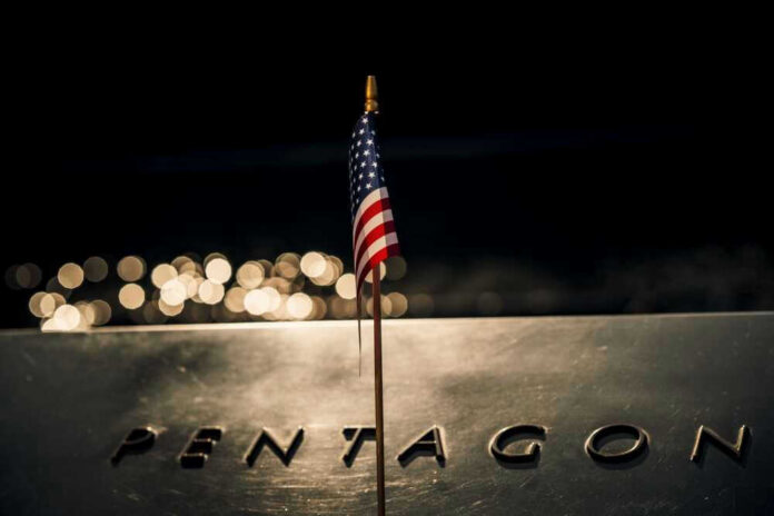 American flag above engraved Pentagon sign at night