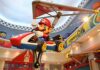 Large statue of Mario in a go-kart with a glider in an amusement park setting