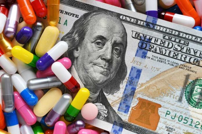 A hundred dollar bill surrounded by various colorful capsules and pills