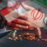 A hand resting on a table with coins stacked in front, overlaid with flags of the US and Iran