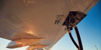 Close-up view of an aircraft wing being fueled at sunset