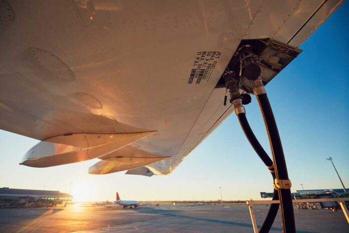 Close-up view of an aircraft wing being fueled at sunset