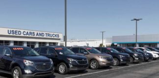 Row of used cars for sale at a dealership with price tags displayed