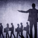 Layoffs EXPOSE AI Crisis Shadows of laid-off workers walking, large figure pointing.
