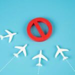 Charging Device CHAOS Diverts Flight! A red prohibition sign surrounded by white airplane models on a blue background