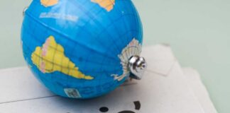 A small globe resting on a newspaper with the word 'crisis'