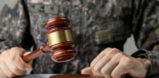 Military person holding gavel near desk
