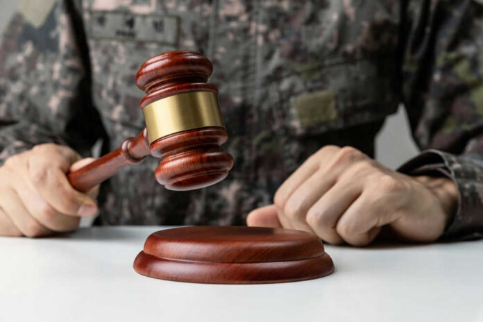 Military person holding gavel near desk