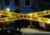 Festival Chaos: Dueling Gunmen Emerge Police tape marking a crime scene with blurred figures in the background