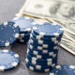 Casino Cash Priest? Parish Rocked Stack of blue poker chips next to cash bills