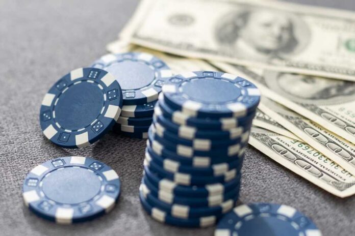 Stack of blue poker chips next to cash bills