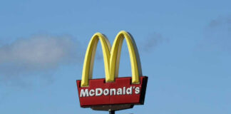McDonalds drive-thru sign against a blue sky.