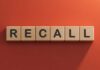 Wooden letter tiles spelling recall on an orange background