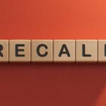 Wooden letter tiles spelling recall on an orange background