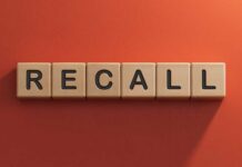 Wooden letter tiles spelling recall on an orange background