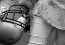Tragedy: NFL Star Dies At 36 Football player holding helmet, dirty uniform close-up.