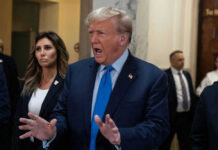 Donald Trump speaking with hands raised in a hallway